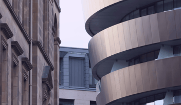 Old stone building alongside a modern curved structure, representing the tension between legacy constraints and new architecture in core banking modernisation
